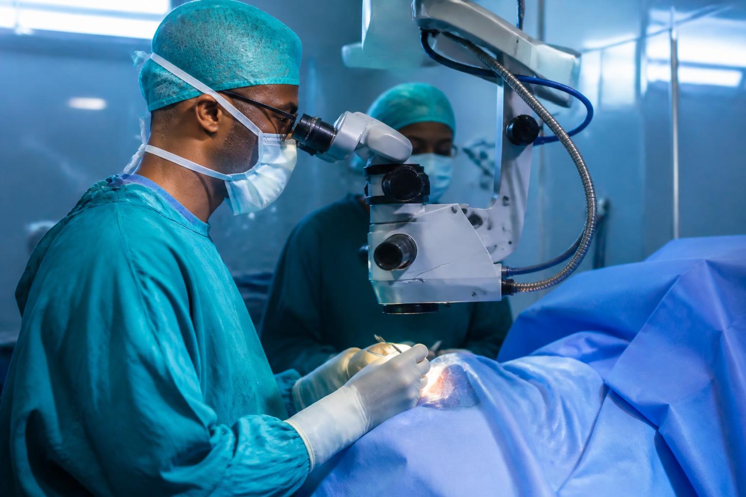 Surgeon performing eye microsurgery under an operating microscope